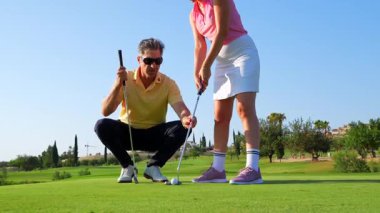 Profesyonel golf eğitmeni, öğrenciye açık hava eğitimi sırasında yeşil ışık veren ve uzman rehberliğini paylaşan spesifik vuruş tekniğini gösteriyor.