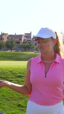 Golf arabası süren genç bayan golfçü, golf sahasında golf sopasıyla poz veriyor, sportif yaşam tarzı ve boş zaman aktiviteleri sergiliyor.