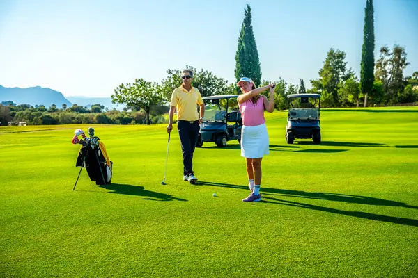 Çiftler golf sahasında güneşli bir günün tadını çıkarıyorlar, birlikte oynuyorlar ve açık havada eğleniyorlar.