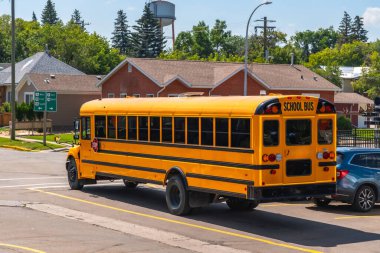 Sarı okul otobüsü gündüz vakti banliyö sokaklarında geziyor, öğrencileri okula getirip götürüyor, eğitimdeki güvenli ve güvenilir ulaşımın önemini vurguluyor