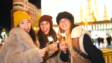 Genç kadınlar Moskova 'da Noel gecesi eğleniyorlar, ellerinde maytaplar ve Kızıl Meydan' ın yakınında gülümsüyorlar.
