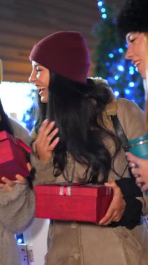 Genç kadınlar Noel hediyelerini gece pazarında değiş tokuş ediyorlar, neşeli atmosferin tadını çıkarıyorlar.