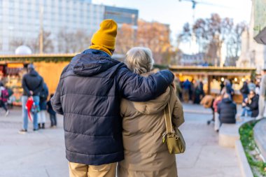 Avrupa 'da kış tatili boyunca açık hava Noel pazarında kucaklaşan yaşlı çift