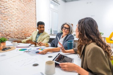 Modern bir ofiste iş birliği yapan çeşitli iş adamları. Verileri analiz etmek ve verimli bir takım toplantısında finansal tabloları tartışmak. Takım çalışması ve profesyonel iletişim gösteriliyor
