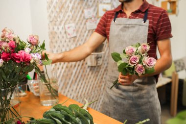 Çiçekçi, bir çiçekçide, ahşap bir masada güzel bir buket yapar..
