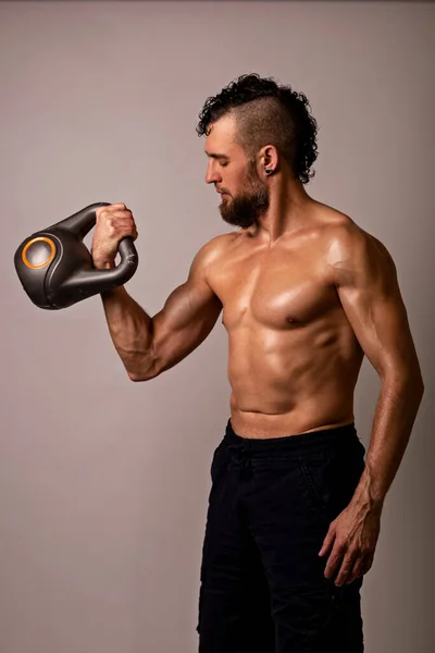 年轻的肌肉男摆设与轻盈背景的水壶铃铛 体育生活方式 — 图库照片