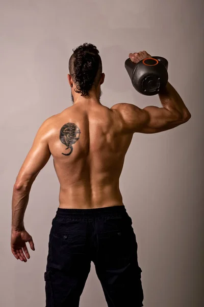 年轻的肌肉男摆姿势 背对着一个浅色背景的水壶 从后面看 体育生活方式 — 图库照片