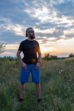 Gün batımında tarlada sakallı ve mohawk saçlı genç bir adam. Doğa.