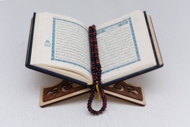 The words on Qoran is arabic words which means the Holy Qoran. Muslim beads and Koran on wooden table. Islamic concept.