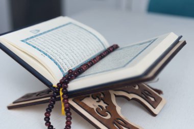 The words on Qoran is arabic words which means the Holy Qoran. Muslim beads and Koran on wooden table. Islamic concept.