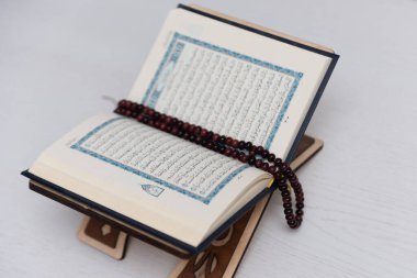 The words on Qoran is arabic words which means the Holy Qoran. Muslim beads and Koran on wooden table. Islamic concept.