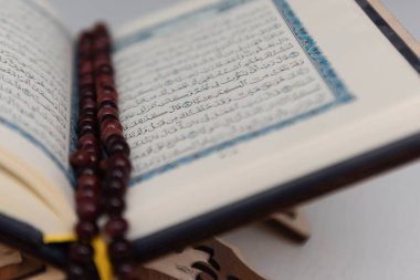 The words on Qoran is arabic words which means the Holy Qoran. Muslim beads and Koran on wooden table. Islamic concept.