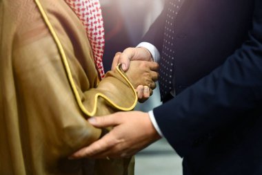 Arap işadamları iş ortağına el sıkışıyorlar.