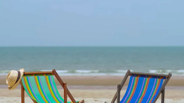 色彩斑斓的海滩椅子 帽子在沙滩上 海浪在海浪中 蓝天在背景 — 图库照片