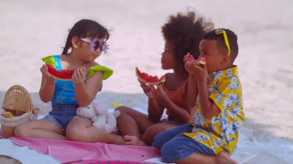 一群孩子在暑假期间在海滩野餐时吃西瓜 — 图库照片