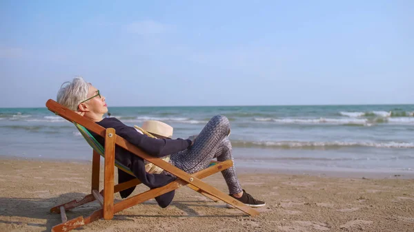 穏やかなビーチでリラックスした高齢のアジアの女性 ストックフォト