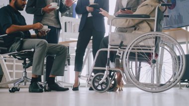 Engelli bir şirket çalışanı ofiste iş arkadaşlarıyla mutlu bir şekilde çalışabilir..