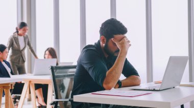 Genç bir şirket çalışanı uzun süre çalışırken yorgun hissediyor..