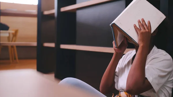 一个女学生坐在图书馆里准备考试时 对看书感到厌烦 — 图库照片