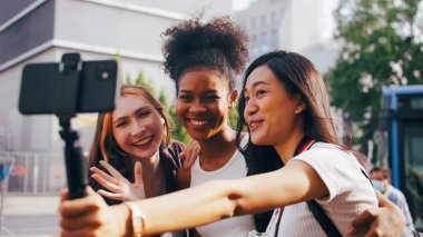 Bir grup çok ırklı bayan arkadaş şehir turunun tadını çıkarıyor. Genç turistler birlikte fotoğraf çekilirken eğleniyorlar..