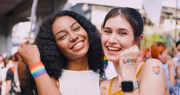 A lesbian couple with a rainbow tattoo sticker representing the symbol of homosexuality in a pride parade.