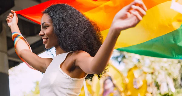 在一场骄傲的游行中 一位年轻的黑人女子挥舞着彩虹旗 象征着同性恋 — 图库照片