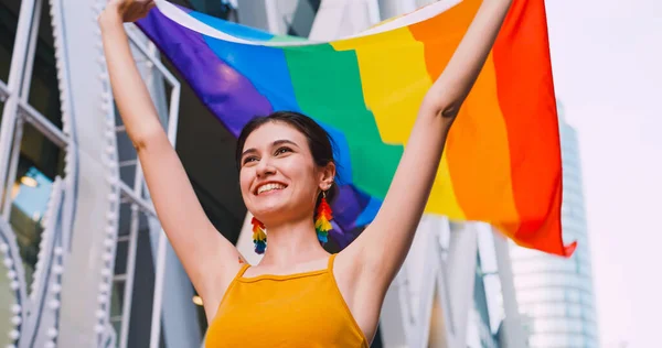 在一场骄傲的游行中 一位年轻女子挥动着彩虹旗 象征着同性恋 — 图库照片