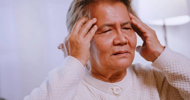 Migren ağrısı olan Asyalı yaşlı bir kadın. Yaşlı kadın baş ağrısı çekiyor..