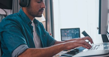 Asyalı müzisyen kendi stüdyosunda yeni müzik yapıyor. Bir besteci bir melodi yaratmak için modern ekipman kullanıyor..