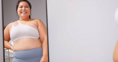 Tombul bir Asyalı kadın aynanın karşısında dikilirken kendinden emin ve gururludur..