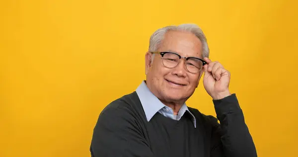 Close up, portrait of older man smiling and looking at the camera. Isolated on yellow background in the studio.