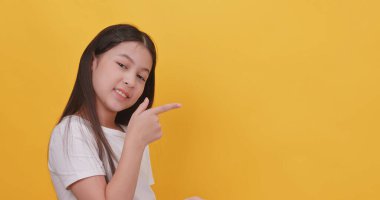 Şirin küçük kız sarı arka planda bir şey gösteriyor..