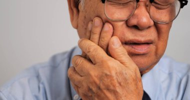 Diş ağrısı çeken Asyalı yaşlı bir adam..