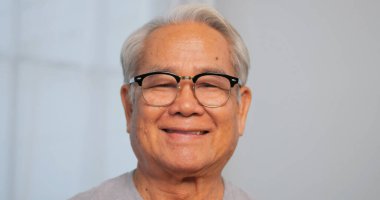 Yakından, yaşlı bir adamın gülümseyen ve kameraya bakan portresi.