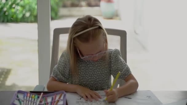 Μικρό Χαριτωμένο Κορίτσι Γυαλιά Κάνει Την Εργασία Ενώ Κάθεται Στο — Αρχείο Βίντεο