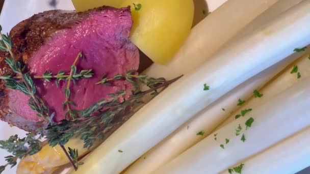 ホワイトアスパラガスの芽と新しいジャガイモでプレートに中希少なステーキを蒸す ドイツ料理の人気料理 縦のビデオ アスパラガスの季節 高品質の4K映像 — ストック動画