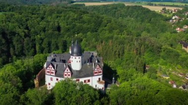 Hava aracı, Rochsburg Ortaçağ kalesini Lunzenau, Saksonya yakınlarındaki ormanlar arasında, nehrin kıyısında, Almanya 'nın 15 Haziran 2023 tarihli kalesini gösteriyor. Yüksek kalite 4k görüntü