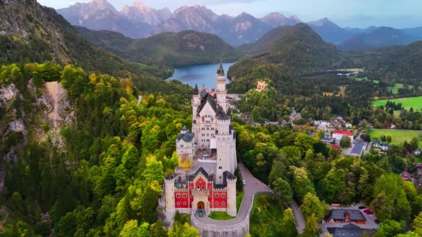 ミュンヘン バイエルン ドイツ ヨーロッパの近くのアルプスの背景にある空中ドローンビューノイシュヴァンシュタイン城 スプルースの森で覆われた山の城と湖と秋の風景 高品質で — ストック動画