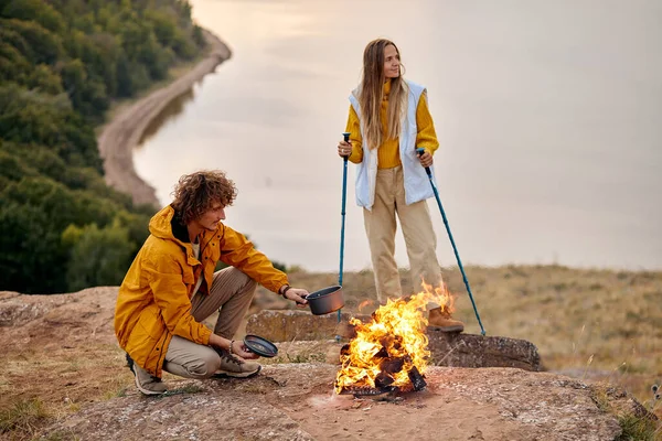 Spring or autumn camping with campfire at night. camping, travel, tourism, hike and people concept. Quality family couple time together during travel.Happy man and woman in sportive clothes in nature