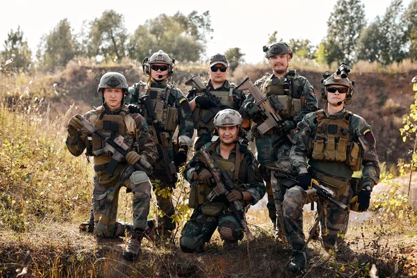 team of confident army rangers before military operation soldiers against, marines preparing for war holding assault machine gun, posing at camera together outdoor, portrait. military forces concept