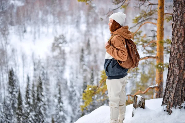 adventurer woman with backpack walking travelling in mountains at frozen winter day. tourism, travel, hiking, inspiration, freedom, lifestyle concept. holidays in countryside, in forest, trip