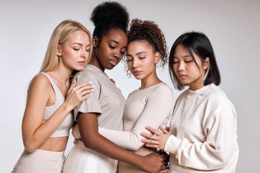 group of attractive multiracial young women with different ethnicity and skin posing together. Pacified black american asian and caucasian ladies leaned on each other, calm. Isolated on white
