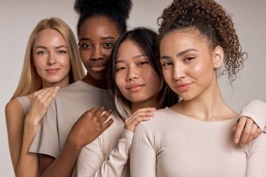 Diversity, multi-ethnic beauty concept. Four smiling beautiful ladies of different races, African, Asian and Caucasian, with natural makeup, posing on studio background, standing in row. beauty
