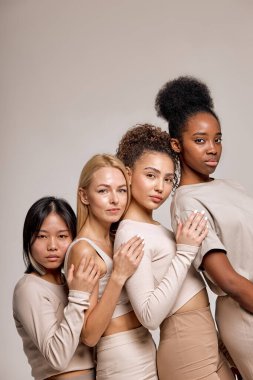 nice caucasian, asian and black american ladies in casual wear posing at camera together, young women isolated over studio background. Portrait of ladies of different ethnicity and appearance