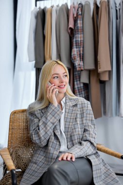 female stylist talking on phone with client or customer, discuss order. Successful Caucasian fashion designer have online smartphone call consultation with consumer at home office.