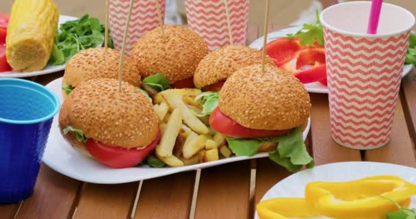 Chutné Hamburgery Hranolky Bílém Talíři Jednorázové Poháry Dřevěném Stole Venku — Stock video