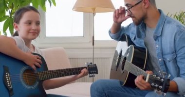 Baba kız gülüyor, günün tadını çıkarıyor. Müzik dersi, öğretim ve öğrenme, büyüme ve sanatsal beceri gelişimi. Enstrüman, müzisyen ve çalmayı öğrenen çocuklu bir adam, ders ve sanat eğitiminde mutlu..
