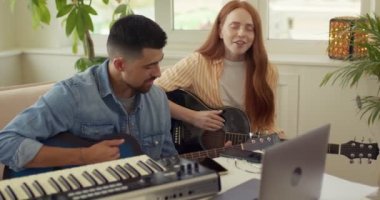 müzik, e-öğrenme teknolojisi konsepti - dizüstü bilgisayarlı genç adam, kadın veya müzisyenler gitar çalmayı öğreniyorlar. Öğretmenli kızıl kız evde yavaş çekim kursuna katılıyor.
