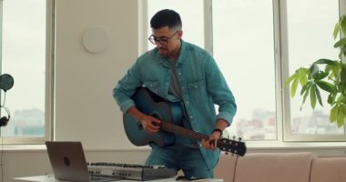 Çevrimiçi müzik okulu. Yetenekli gitar öğretmeni öğrencilerle konuştuğunu anlatıyor. Uzaktan öğrenme. Gitarist evde dizüstü bilgisayarda telli çalgı dersi veriyor. Yavaş çekim.