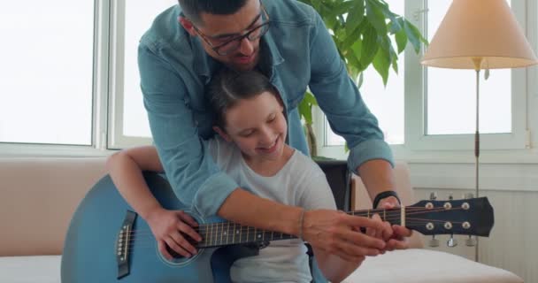 笑着的年轻父亲帮助他的女儿拿着乐器试着教她弹吉他 现代家庭 快乐的回忆 慢动作 家庭传统生活方式嗜好 — 图库视频影像